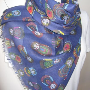 May include: A navy blue scarf with a fringed edge features a repeating pattern of colorful Russian nesting dolls.
