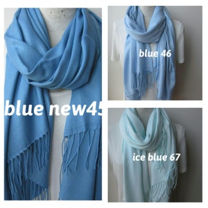 May include: Three different colored scarves, one blue, one light blue, and one ice blue. Each scarf has a fringe on the bottom.