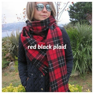 May include: A red and black plaid scarf with white accents. The scarf is folded and draped around a person's neck.