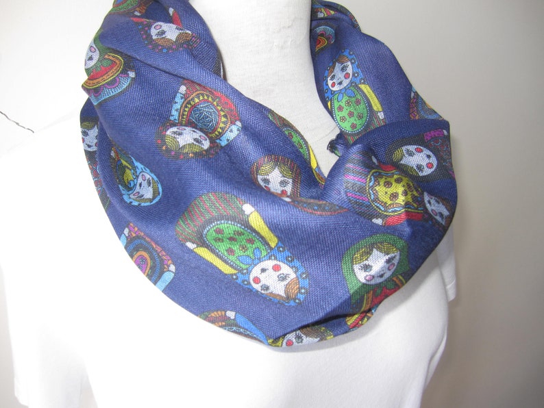 May include: A navy blue infinity scarf with a colorful pattern of Russian nesting dolls.