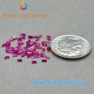 Könnte beinhalten: Eine Ansammlung kleiner, rechteckiger, magentafarbener Edelsteine, die auf einer grauen Oberfläche verstreut sind. Eine US-amerikanische 10-Cent-Münze dient zum Größenvergleich. Der Text "Prime Gem Source" und "SHIPS FROM USA" sind sichtbar.