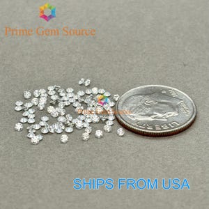 Puede incluir: Un montón de pequeños diamantes redondos y transparentes, esparcidos sobre una superficie gris. Una moneda de diez centavos de dólar estadounidense se incluye para comparar el tamaño. El texto "SHIPS FROM USA" es visible en la parte inferior de la imagen.