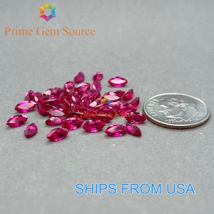 May include: A pile of 20 small, bright pink, marquise-shaped gemstones, next to a US dime coin for scale.
