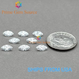 May include: Marquise-cut gemstones displayed with a US quarter for size comparison. The gemstones are clear and faceted, reflecting light. The image includes the text "Prime Gem Source" and "SHIPS FROM USA".