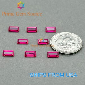 Puede incluir: Se muestran varias piedras preciosas rectangulares de color rosa brillante, posiblemente rubíes. Se incluye una moneda de veinticinco centavos estadounidense para comparar el tamaño. También aparece el texto "Prime Gem Source" y "SHIPS FROM USA".