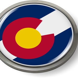 Op de afbeelding: Een ronde metalen pin met een glanzende afwerking met de vlag van Colorado. De vlag heeft een grote rode cirkel met een gele cirkel in het midden, omringd door een witte cirkel en een blauwe cirkel.