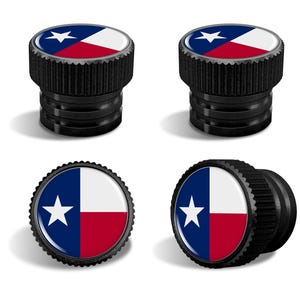 May include: Set of four black valve stem caps featuring the Texas state flag design. The caps have a textured, ridged edge and a glossy, circular emblem with a blue star, white, and red sections.