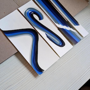 May include: Three rectangular white paper bookmarks featuring abstract hand-painted designs in shades of navy blue, royal blue, light blue, and black. The artwork consists of fluid, sweeping brushstrokes that create curved and linear patterns.