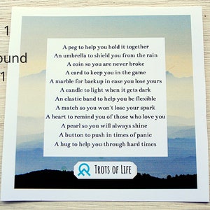 May include: A watercolor painting of a mountain range with a blue sky and clouds. The painting has a poem printed on it that reads: "A peg to help you hold it together, An umbrella to shield you from the rain, A coin so you are never broke, A card to keep you in the game, A marble for backup in case you lose yours, A candle to light when it gets dark, An elastic band to help you be flexible, A match so you won't lose your spark, A heart to remind you of those who love you, A pearl so you will always shine, A button to push in times of panic, A hug to help you through hard times." The painting is signed "TROTS OF LIFE".