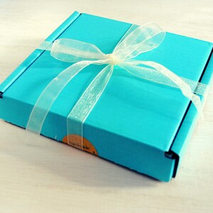 May include: A turquoise blue gift box with a white satin ribbon tied in a bow. The box has a label that says "remarkable".