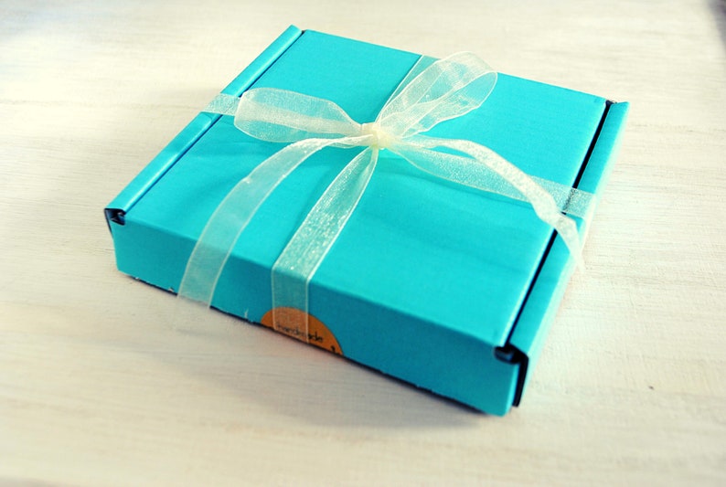 May include: A turquoise blue gift box with a white satin ribbon tied in a bow. The box has a label that says "remarkable".