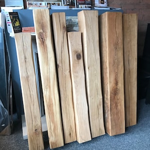 May include: A collection of seven reclaimed wood beams, varying in length and width, with a natural wood finish. The beams have a rustic appearance with knots and grain patterns.