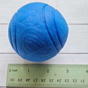 May include: A bright blue rubber dog toy ball with a textured surface. The ball is approximately 2 inches in diameter.