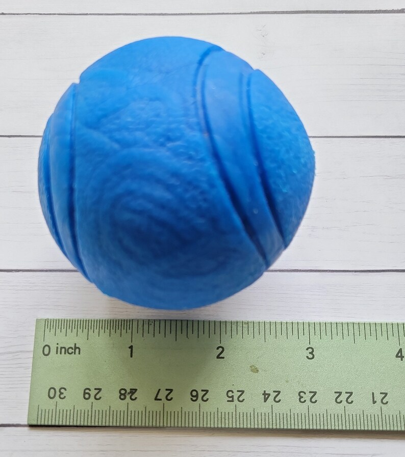 May include: A bright blue rubber dog toy ball with a textured surface. The ball is approximately 2 inches in diameter.