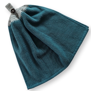 May include: Teal hanging kitchen towel with a gray crocheted top and a wooden button closure. The towel is made of a soft, absorbent material and has a loop for hanging. The towel is approximately 18 inches long and 12 inches wide.
