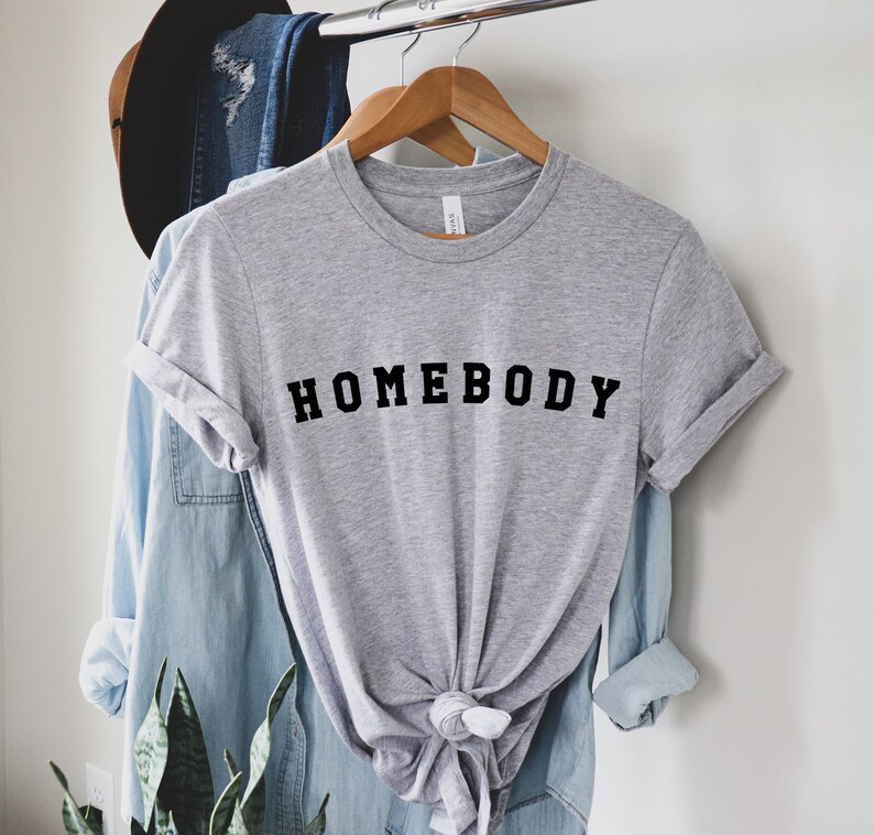 May include: A gray t-shirt with the text "HOMEBODY" printed in black letters.