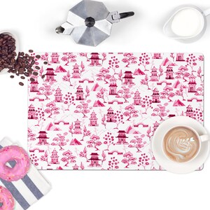 May include: Pink and white patterned placemat with a repeating design of Chinese pagodas, trees, and mountains.