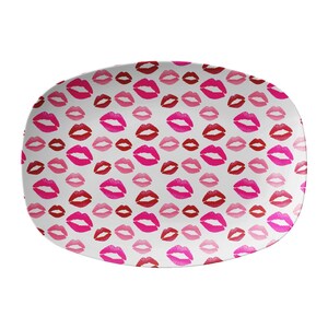 May include: White oval serving platter with a repeating pattern of red, pink, and fuchsia lipstick kiss marks. The platter has rounded edges and a smooth surface, perfect for serving appetizers or desserts.