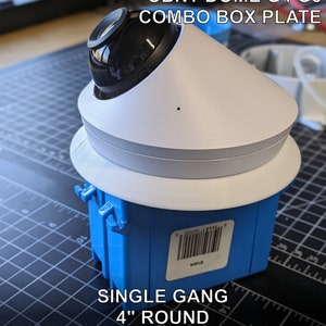May include: A white and black security camera mounted on a blue electrical box. The camera has a dome shape and is labeled "AnalogNMD UBNT DOME G4 G5 COMBO BOX PLATE". The box is labeled "SINGLE GANG 4" ROUND OUTDOOR POLYCARBONATE".