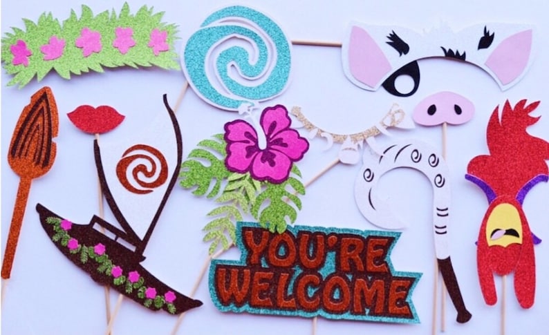 Puede incluir: Un conjunto de 11 accesorios para cabina de fotos con tem&aacute;tica de Moana. Los accesorios est&aacute;n hechos de cartulina con brillantina y presentan personajes y objetos de la pel&iacute;cula, incluyendo una flor, un barco, un cerdo, un gallo y un cartel que dice "Bienvenido".