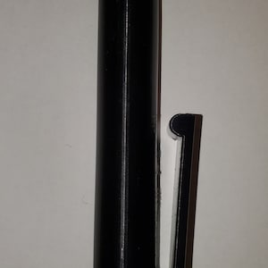 Puede incluir: Un soporte de plástico negro para un bolígrafo o un lápiz. El soporte tiene un clip en el lateral para sujetarlo a un bolsillo o una bolsa.