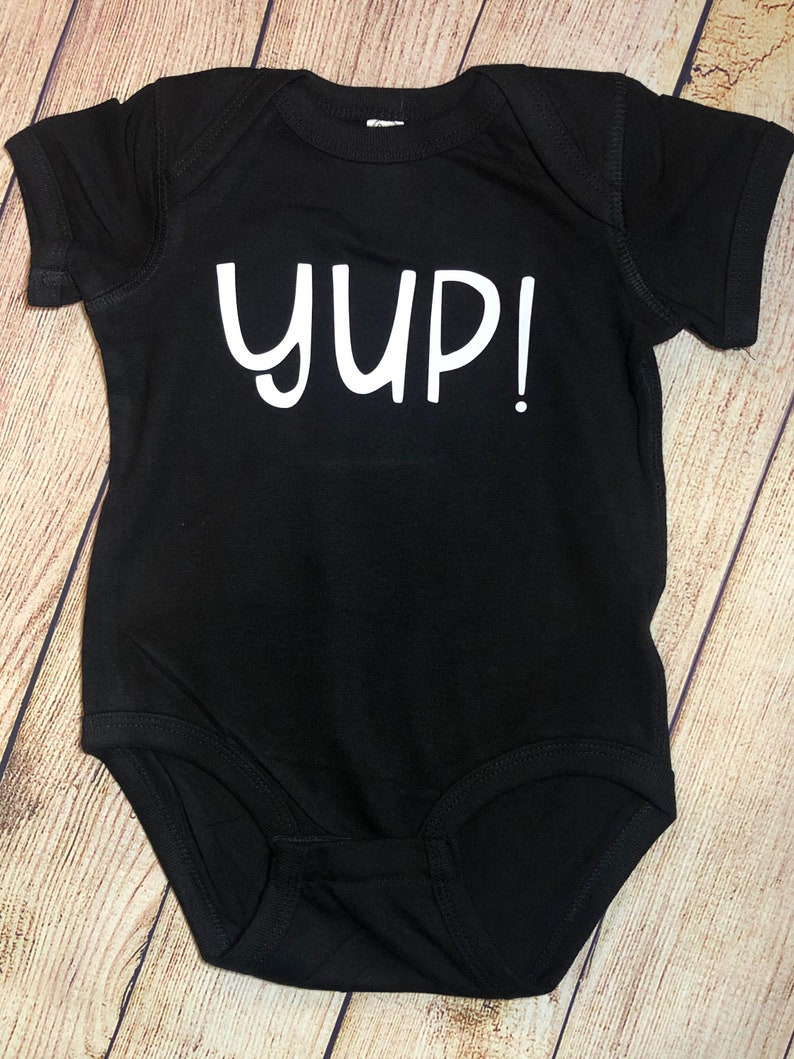 Peut inclure: Combinaison noire pour b&eacute;b&eacute; avec le texte blanc "YUP!"