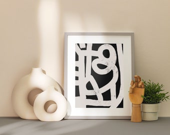 Puede incluir: Dos jarrones de cerámica blanca con un diseño de corte circular, una impresión abstracta en blanco y negro enmarcada, una figurita de mano de madera y una planta verde en maceta sobre una superficie gris.
