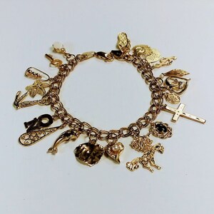 Pode incluir: Um bracelete de ouro com uma variedade de pingentes, incluindo um golfinho, um cora&ccedil;&atilde;o, uma cruz, um unic&oacute;rnio, uma concha, uma estrela do mar, uma chave e o n&uacute;mero "20".