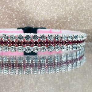 May include: A pink pet collar with two rows of clear rhinestones and a row of pink rhinestones.