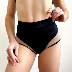 Peut inclure: Short noir taille haute avec un panneau en mesh transparent sur les c&ocirc;t&eacute;s. Le short est fait d'un tissu extensible et confortable.