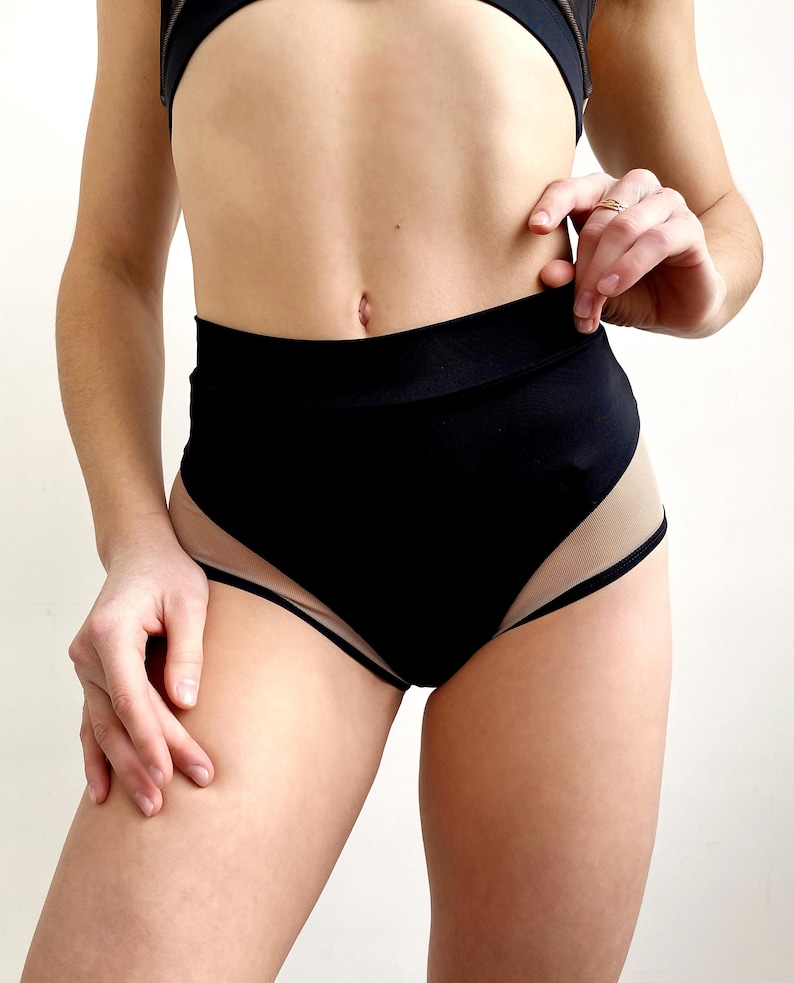 Peut inclure: Short noir taille haute avec un panneau en mesh transparent sur les c&ocirc;t&eacute;s. Le short est fait d'un tissu extensible et confortable.