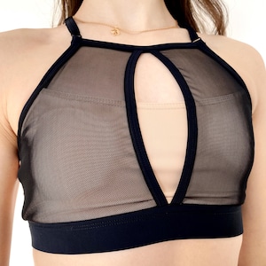 Peut inclure: Top de culture noir en mesh avec une d&eacute;coupe en forme de trou de serrure &agrave; l'avant. Le haut a un d&eacute;collet&eacute; de style halter et une bande noire en bas.