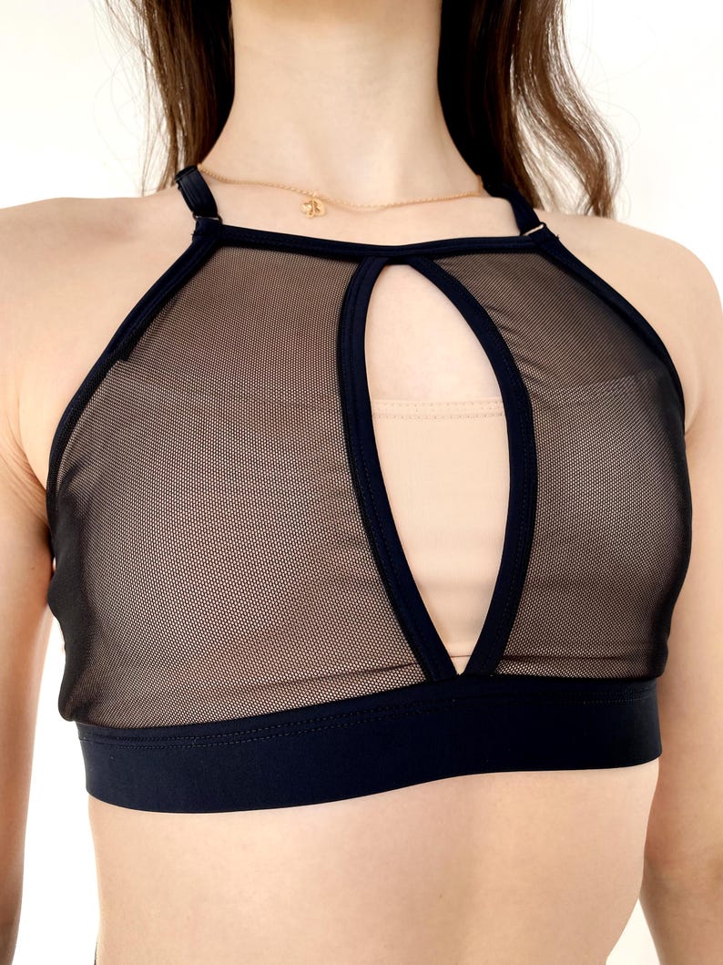 Peut inclure: Top de culture noir en mesh avec une d&eacute;coupe en forme de trou de serrure &agrave; l'avant. Le haut a un d&eacute;collet&eacute; de style halter et une bande noire en bas.