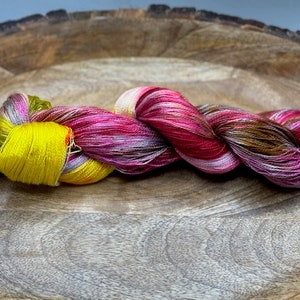 May include: A skein of yarn in shades of pink, brown, yellow, and white. The yarn is twisted and knotted, creating a textured look.