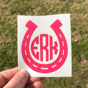 May include: Pink vinyl decal of a horseshoe with the monogram "ERK" inside.