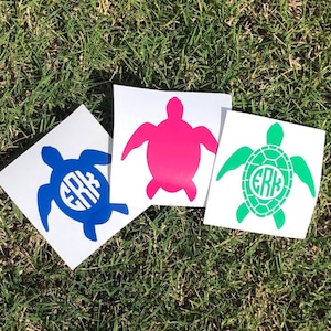 May include: Three turtle stickers with a monogram in the center. The turtles are blue, pink, and green.