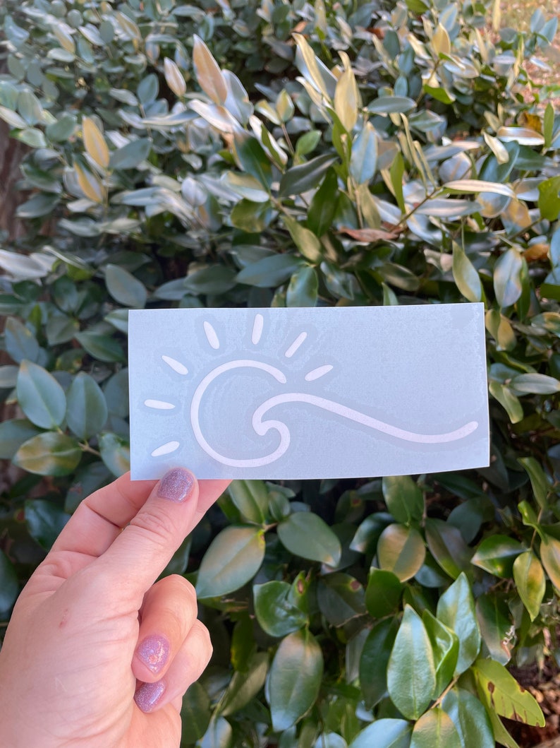 May include: White vinyl sticker with a sun and wave design on a light blue background.