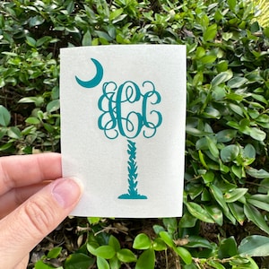 May include: A teal green palm tree with a crescent moon above it and the letters "CCC" in a monogram style.