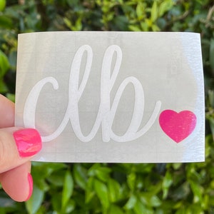 May include: White vinyl decal with the word "clb" written in cursive script. A small pink heart is to the right of the word.