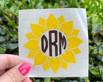 May include: A yellow sunflower decal with a brown circle in the center. The circle contains the letters "DRM" in a brown font.