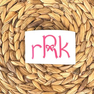 K&ouml;nnte beinhalten: Ein wei&szlig;er Aufkleber mit einem rosafarbenen Monogramm "RRK" mit einer rosafarbenen Schleife in der Mitte des "R".