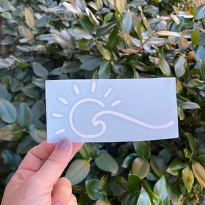 May include: A white vinyl sticker with a sun and wave design on a light blue background.