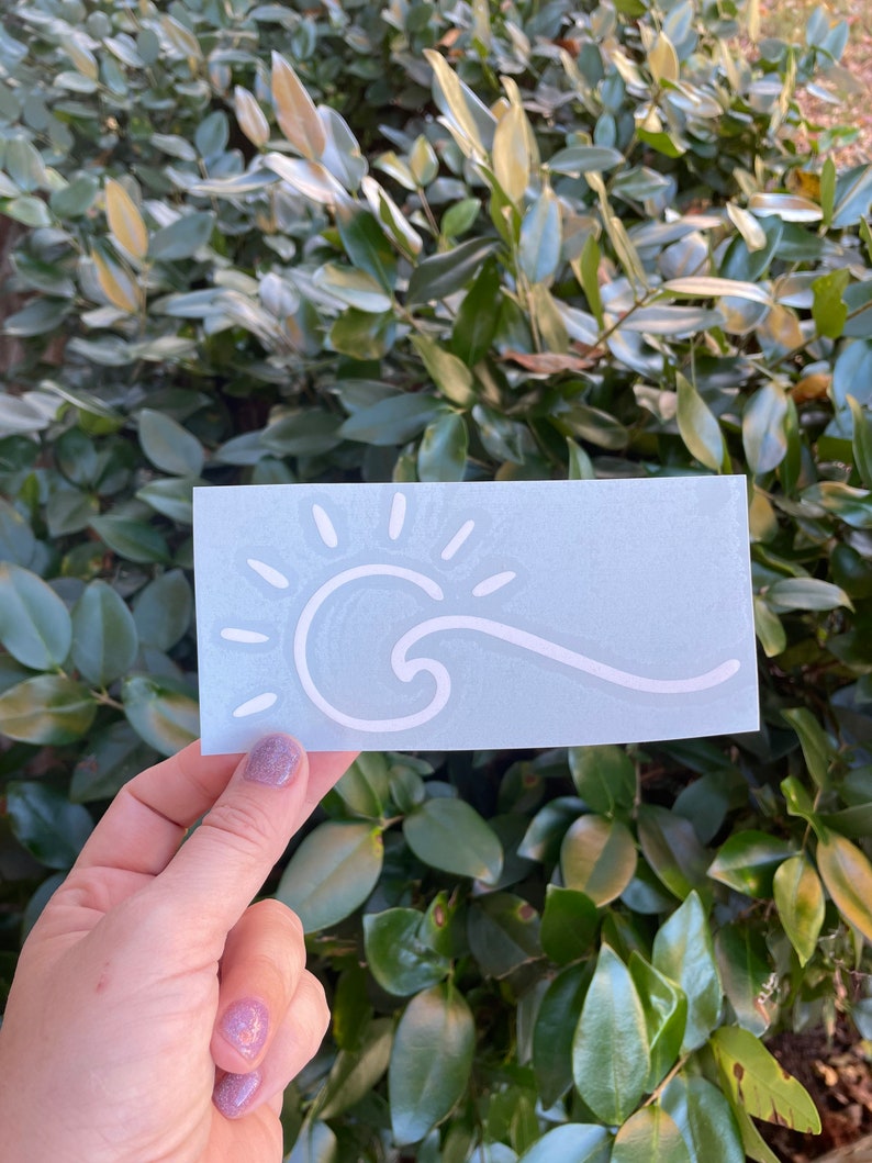 May include: A white vinyl sticker with a sun and wave design on a light blue background.