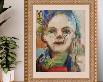 May include: Abstract portrait painting in a gold ornate frame. The artwork features a face with blue, green, red, and brown brushstrokes. The painting is displayed on a wooden surface next to a potted plant.