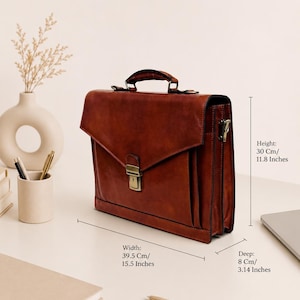 Pu&ograve; includere: Una ventiquattrore in pelle marrone con manico superiore e chiusura in metallo color ottone. La borsa misura 30 cm di altezza, 39,5 cm di larghezza e 8 cm di profondit&agrave;. Presenta una forma rettangolare strutturata con chiusura a patta.