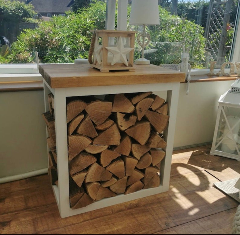 May include: White wood log rack with a wooden top. The rack is filled with stacked firewood.