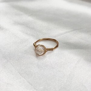 Puede incluir: Un anillo de alambre dorado con un cristal facetado transparente.
