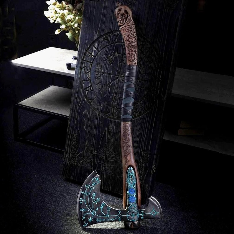 May include: A detailed, decorative axe with a wooden handle and a metal blade. The handle is wrapped in black leather and features intricate carvings. The blade has a teal-colored design and two blue gems. The axe is leaning against a dark wooden panel.