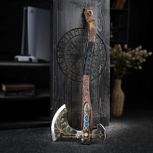 May include: A detailed, decorative axe with a wooden handle and a silver blade. The handle features intricate carvings and is wrapped with leather. The blade has gold-colored etchings and three blue gems. The axe is leaning against a dark wooden panel.