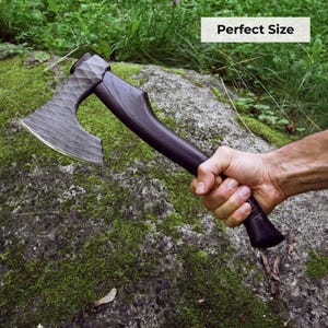 May include: A hand axe with a dark, textured metal head featuring a cross-hatched pattern and a smooth, dark wooden handle. The axe head has a curved, sharpened edge. The text "Perfect Size" is visible in the upper right corner of the image.